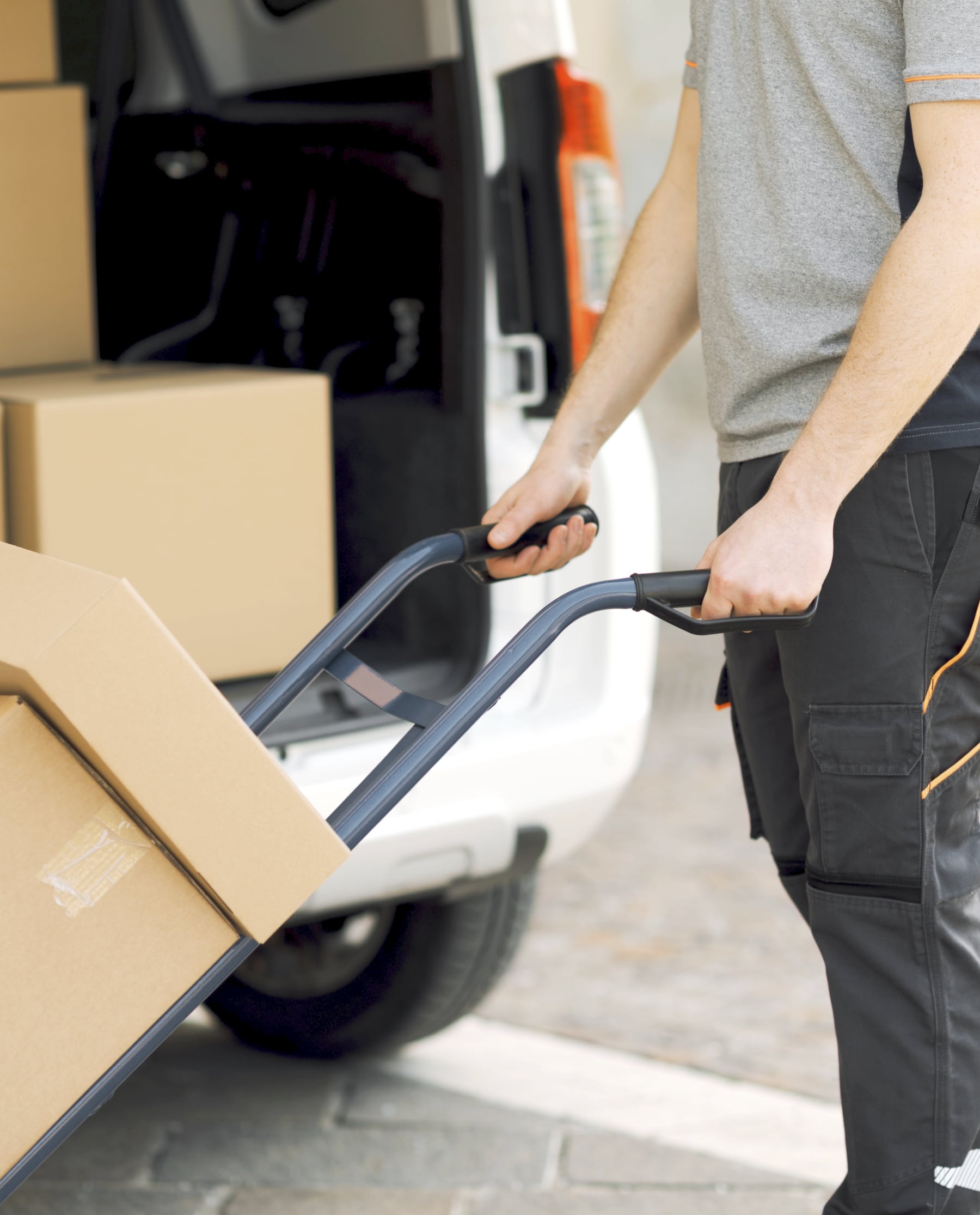 Besku-Logistics-muuttopalvelut-yrityksille-ja-yksityisille-Uusimaa-Helsinki-Vantaa-Espoo-muuttofirma-muutot Nuori nainen nostaa trukilla paketteja hyllyyn logistiikan varastohallissa.